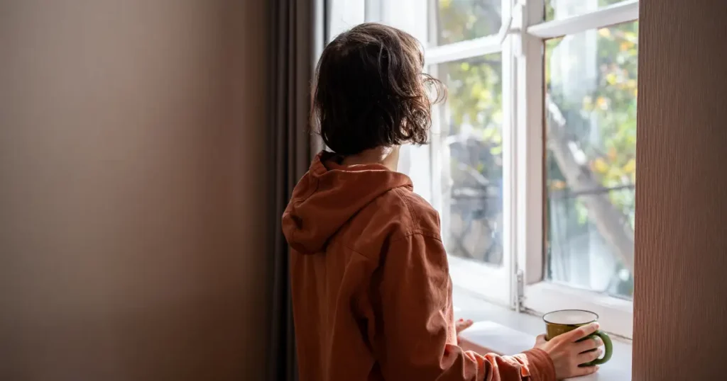 an introverted women standing in front of the window and thinking about enhance her inner world