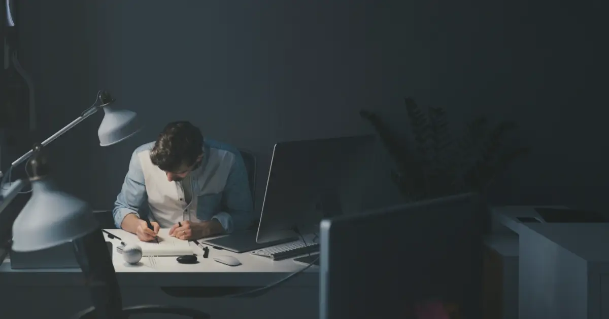 an introverted man sitting at a desk writing on a notepad which indicates introverts rule deep work